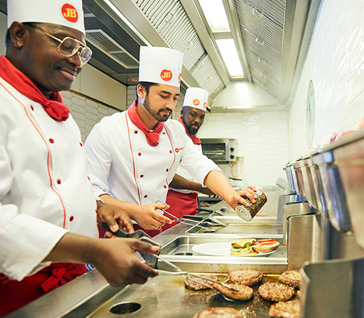 Restaurantküche im Jungfernstieg  Drei Jim Block Köche bereiten Burger-Patties in einer Restaurantküche zu.